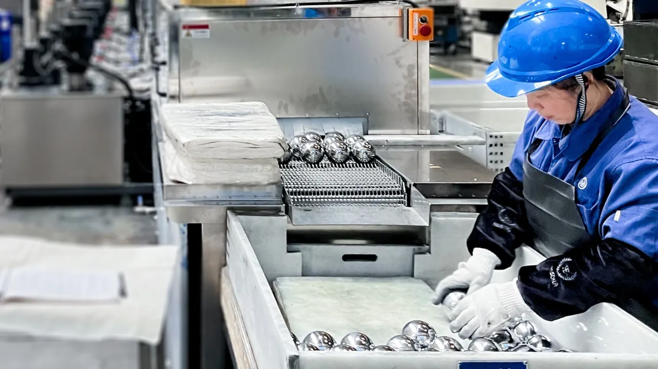 Frau in Arbeitskleidung hält Stahlkugeln