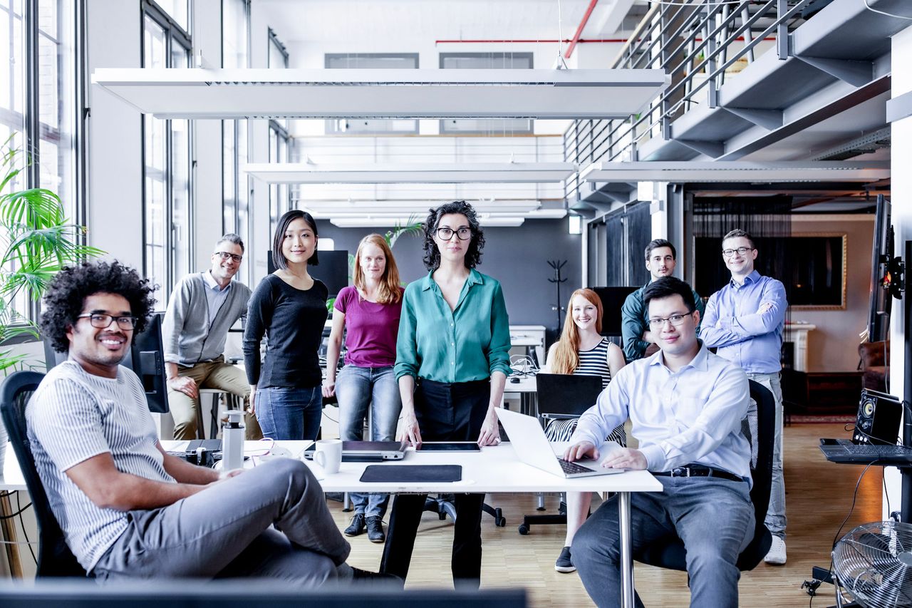 Nove persone siedono o stanno insieme in una stanza