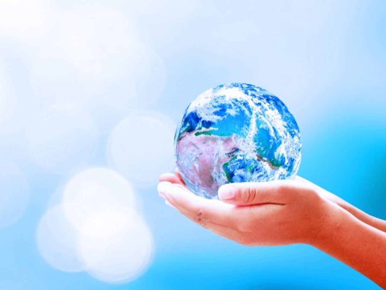 Due mani tengono un globo di vetro in una mano su uno sfondo blu